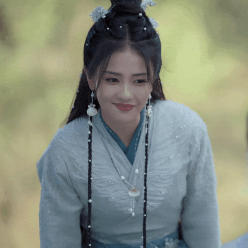 a woman with braids and pearls in her hair is wearing a blue shirt