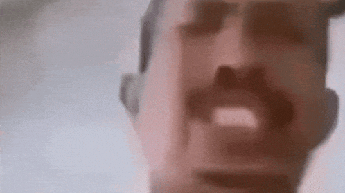 a close up of a man 's face with a mustache and mouth open .