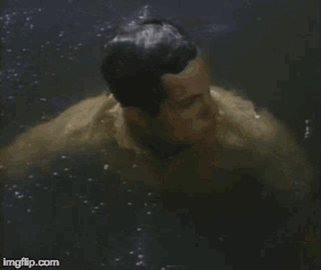 a man in a yellow shirt is swimming in a pool of water .