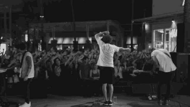 a man stands on stage in front of a crowd in front of a store that says h & m