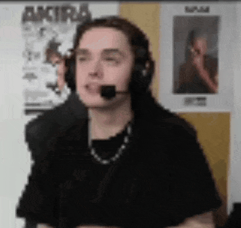a man wearing headphones and a microphone is making a face .