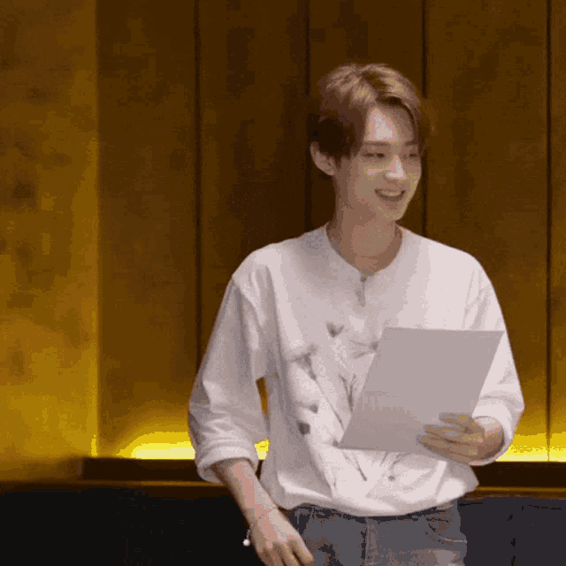 a man in a white shirt is holding a piece of paper in his hand