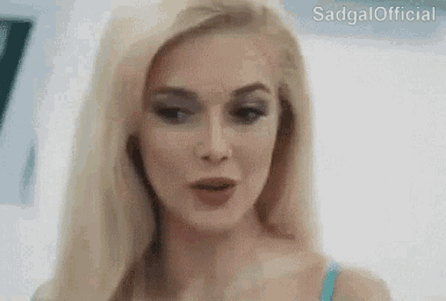 a close up of a woman 's face with a blue top on .