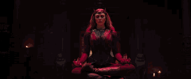 a woman in a red dress is casting a spell with a red light coming out of her hands