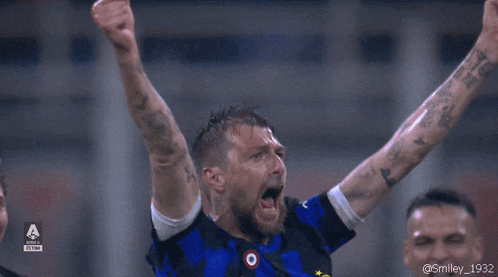 a soccer player celebrates a goal with his arms in the air