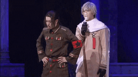 two men in military uniforms are standing on a stage holding hands .