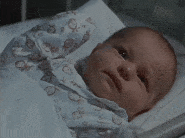 a baby is laying in a hospital bed wearing a pajama with smiley faces and fish on it