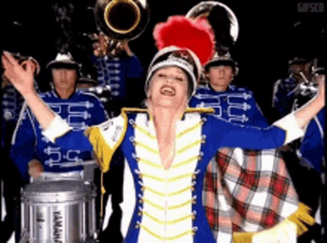 a woman in a marching band uniform is standing in front of a yamaha drum