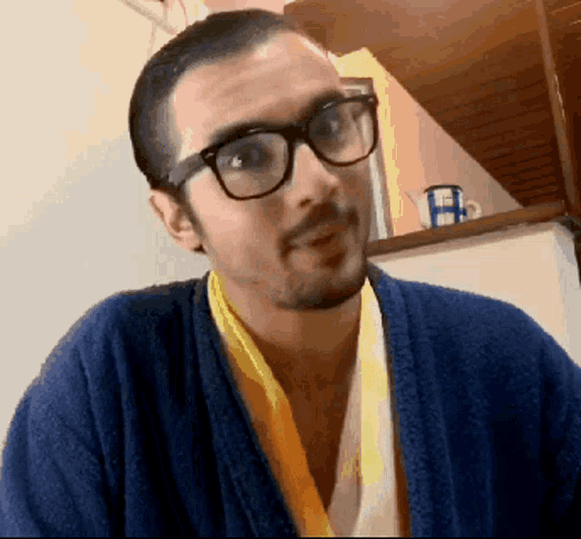 a man wearing glasses and a blue robe with a yellow scarf around his neck