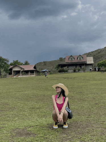 a woman in a straw hat is squatting in a field