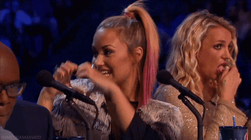two women are sitting in front of microphones and one has a drink in her hand