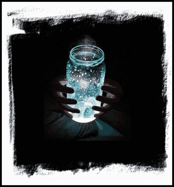 a person holding a mason jar with a light inside of it