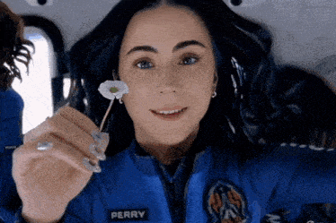 a woman wearing a perry jacket holds a flower