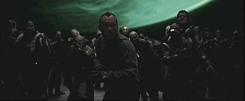 a group of people are standing in a dark room with a man standing in the foreground looking up at the sky