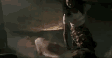 a woman is standing next to a man in a dark room in a movie .