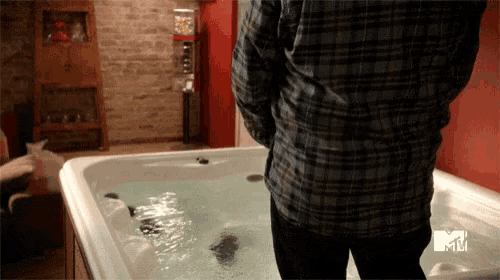 a man in a plaid shirt is standing next to a hot tub that says mtv
