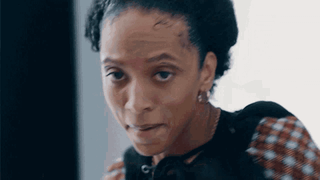 a woman with a scar on her forehead looks at the camera with a serious look on her face