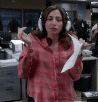 a woman wearing headphones is holding a piece of paper in an office .