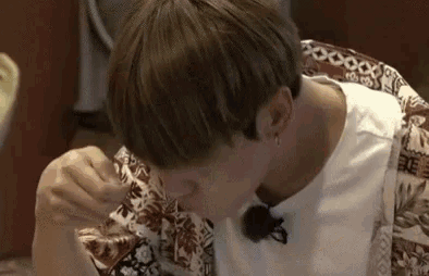 a young man is sitting at a table eating a piece of food .