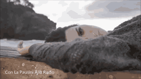 a woman is laying on the beach with her head on a wooden pier .
