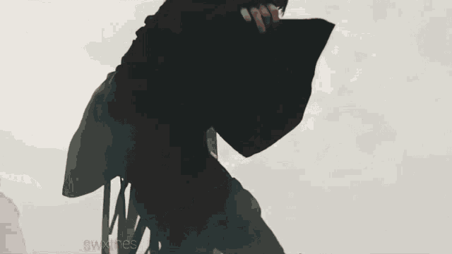 a man in a black cape is standing in front of a flag