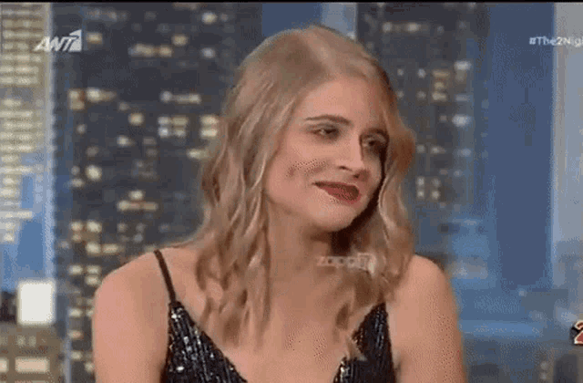 a woman in a black dress is making a funny face while sitting in front of a city skyline .