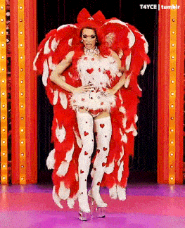 a drag queen is standing on a stage wearing a red and white feathered costume .