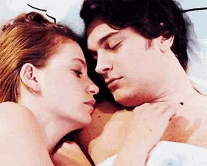 a man and a woman are laying next to each other in bed