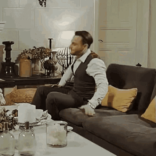 a man is sitting on a couch in a living room with a table .