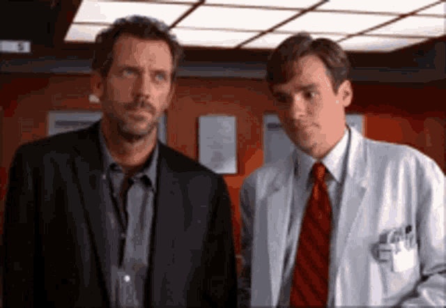 two men in suits and ties are standing next to each other in a room