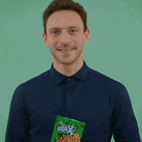 a man in a blue shirt holds a bag of grax french fries