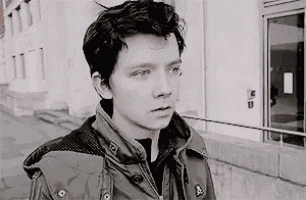 a black and white photo of a young man wearing a jacket .