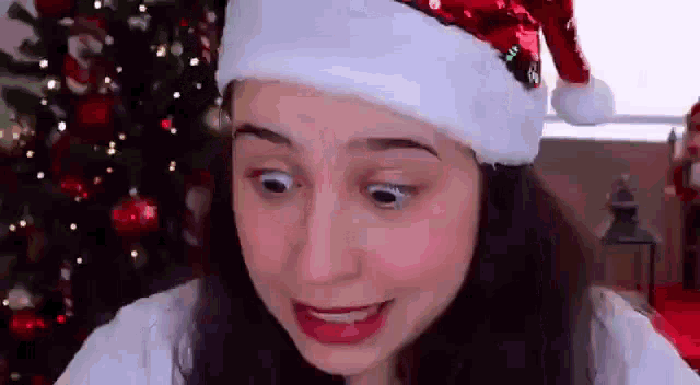 a woman is wearing a santa hat and making a funny face .