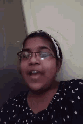 a young girl wearing glasses and a headband is smiling .