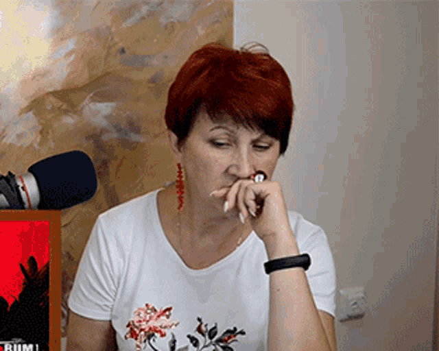 a woman with red hair is sitting in front of a microphone with the word rum on the screen behind her