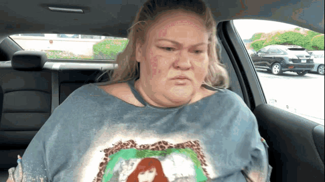 a woman in a car wearing a t-shirt with a picture of a girl on it