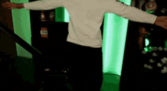 a man with his arms outstretched is standing in front of a green light
