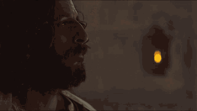 a close up of a man 's face with a yellow light behind him