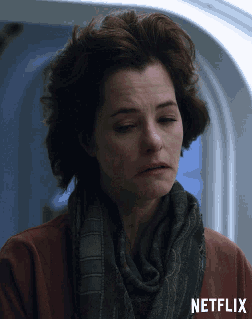 a woman wearing a scarf and a red shirt with netflix written on the bottom