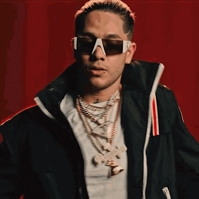a man wearing sunglasses and a necklace with a pendant that says ' gucci ' on it