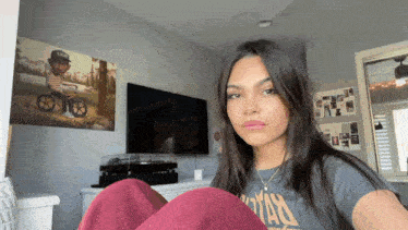 a woman wearing a t-shirt that says ' vans ' on it sits in front of a television