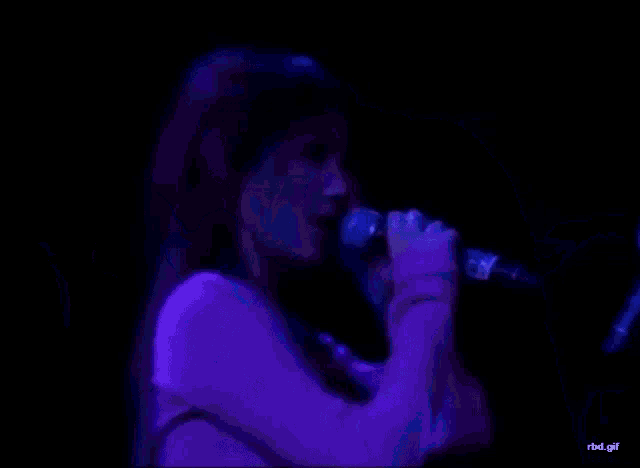 a man singing into a microphone next to a woman in a pink top
