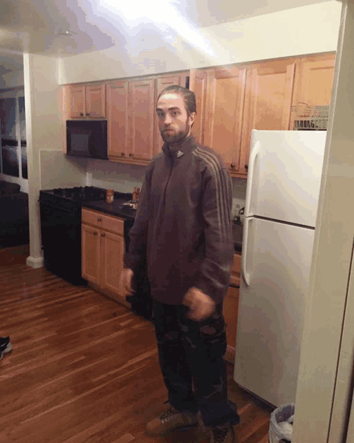 a man is standing in a kitchen with a white refrigerator