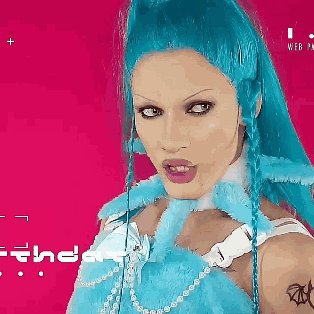 a woman with blue hair and a tattoo on her arm is wearing a blue fur coat .