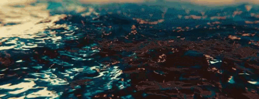a close up of a body of water with waves and a city in the background .