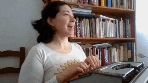 a woman in a white shirt is playing a keyboard in front of a bookshelf full of books