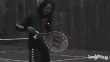 a man is holding a tennis racquet on a tennis court with imgplay written on the bottom