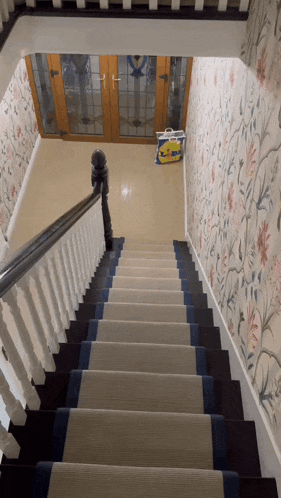 a staircase with a floral wallpaper and a yellow bag on the bottom of the stairs
