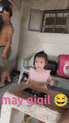 a little girl in a pink dress sits in a cardboard box with may gigil written on the bottom