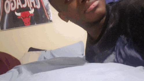 a man laying on a bed with a chicago bulls poster on the wall